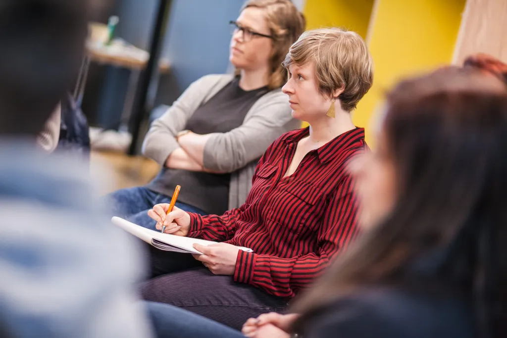 Workshop-Teilnehmerinnen hören aufmerksam zu und schreiben mit